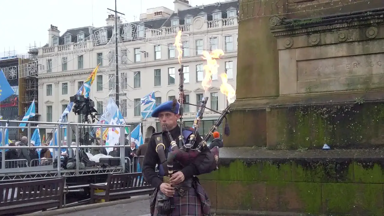 A slow motion and close-up of a piper playing music while fire comes out his pipes