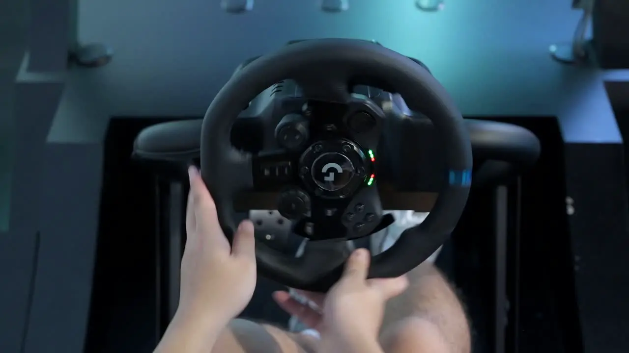 A Chinese gamer plays and uses a car wheel from a themed racing videogame as visitors attend the Hong Kong Computer and Communications Festival in Hong Kong