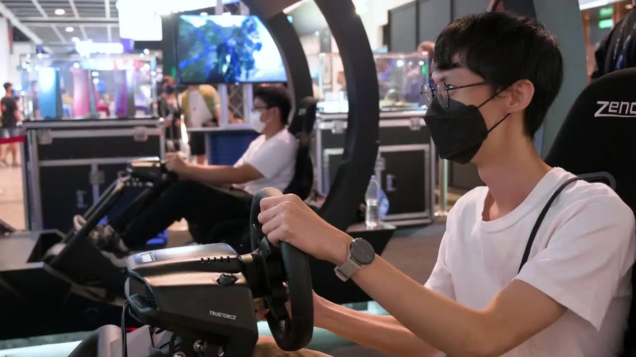 Chinese gamers play a themed racing videogame as visitors attend the Hong Kong Computer and Communications Festival in Hong Kong