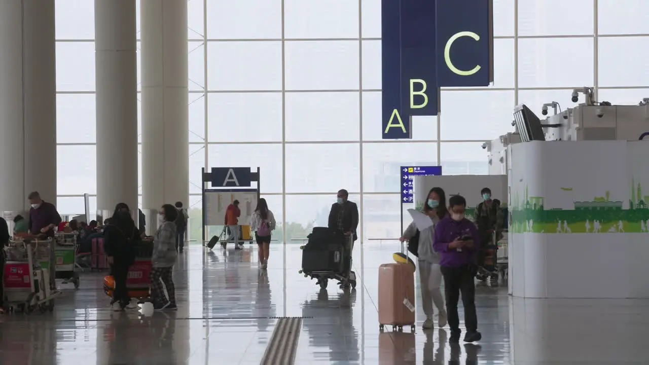 Passengers and travelers are seen walking through the airline check-in and departure hall in Hong Kong's Chek Lap Kok International Airport