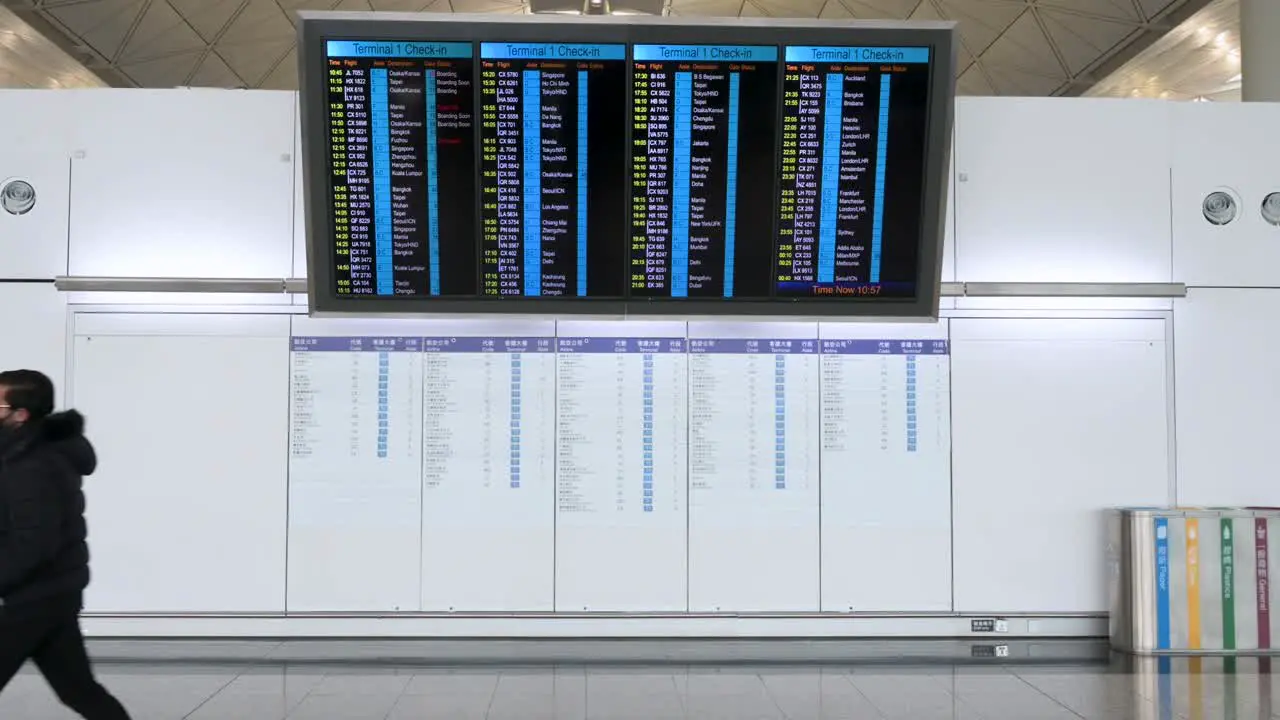 A travel passenger is seen walking past an airline check-in screen at the departure hall in Hong Kong's Chek Lap Kok International Airport