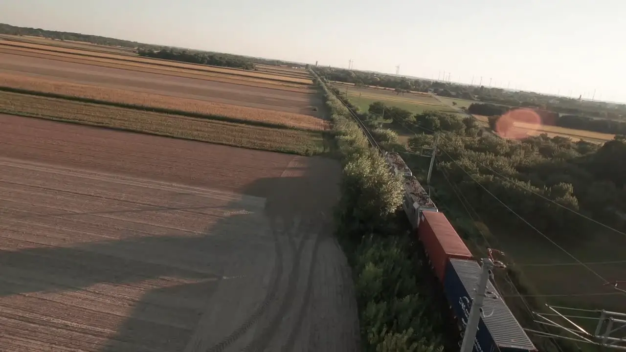 A cinematic drone footage of a train traversing a vast cornfield bathed in the warm hues of an autumn evening