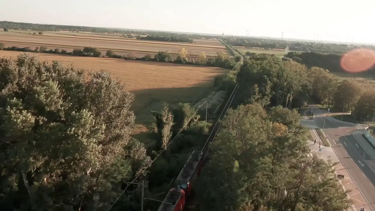 Captivating aerial drone footage follows a laden cargo tank train passing through vast golden-lit cornfields as the drone soars above revealing the stunning rural scenery