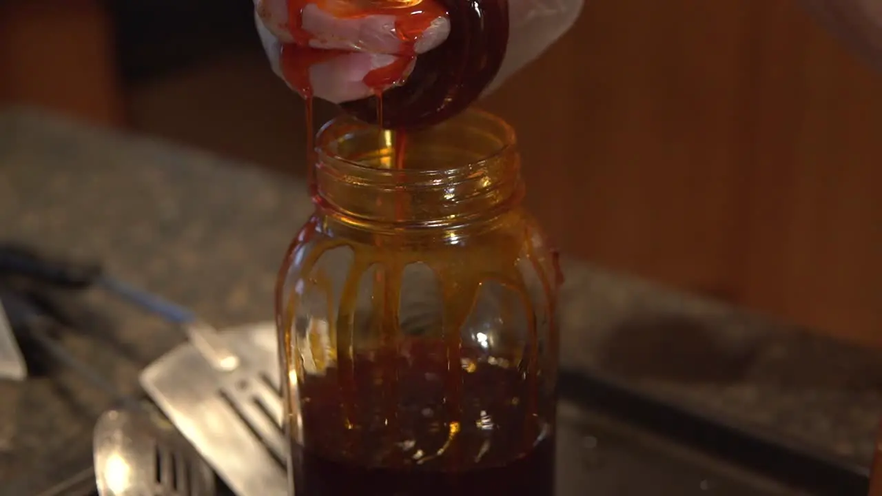 Cayenne and CBD infused coconut oil running over a man's fingers and into a jar