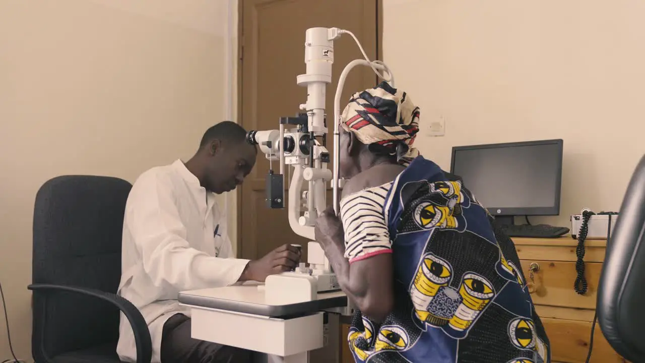 African Doctor checking eye sight of patient in eye hospital and doctor moving equipment and setting head of patient on the correct place for adjustments