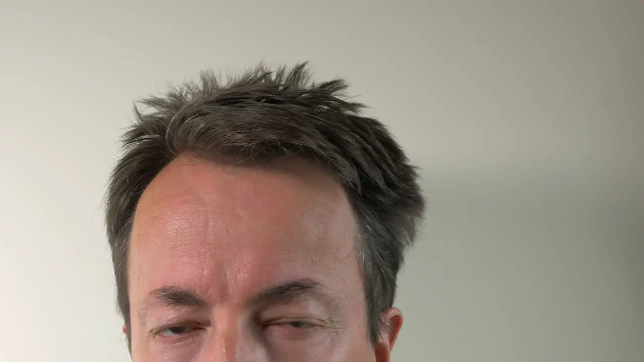 Man Takes Temperature With Digital Thermometer On Forehead