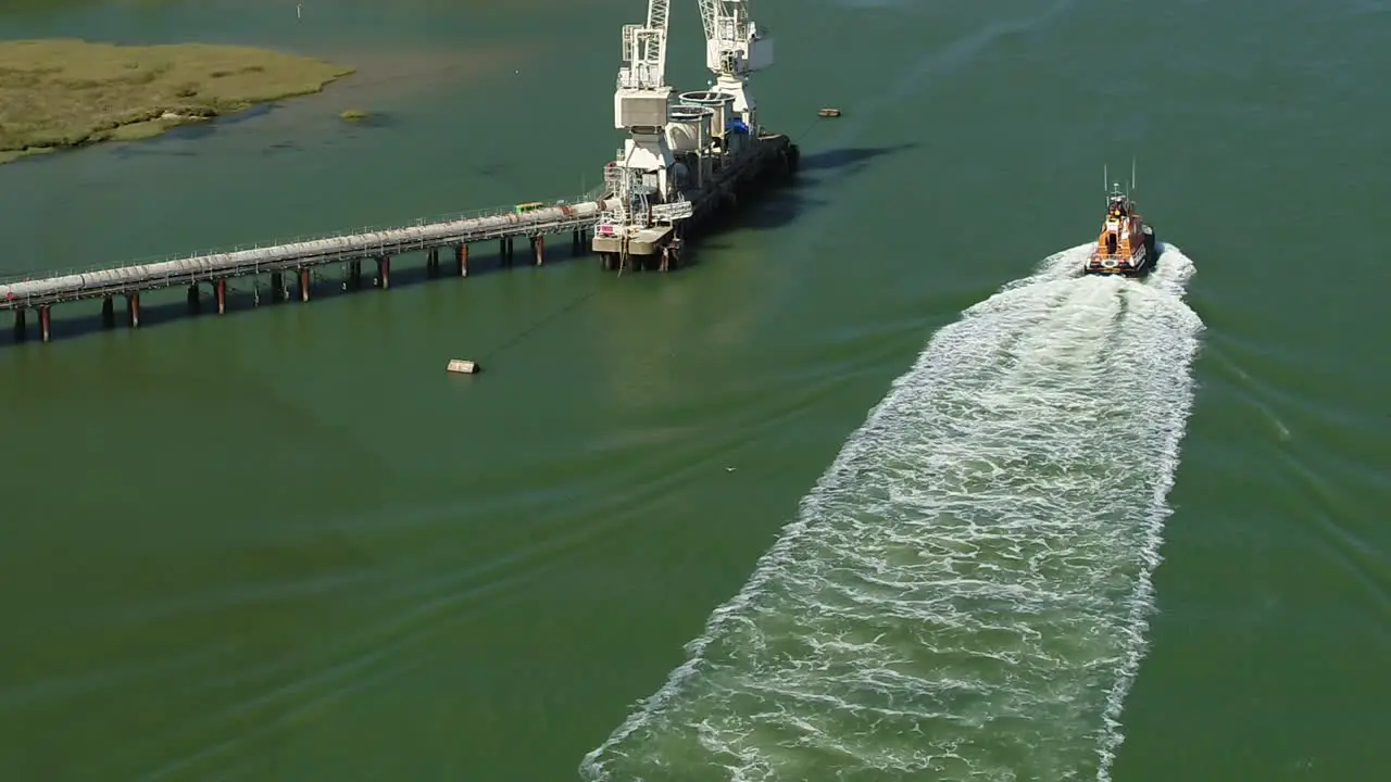 Aerial tracking shot of a RNLI Lifeboat crew sailing down the Swale Estuary between Kemsely and the Isle Of Sheppey