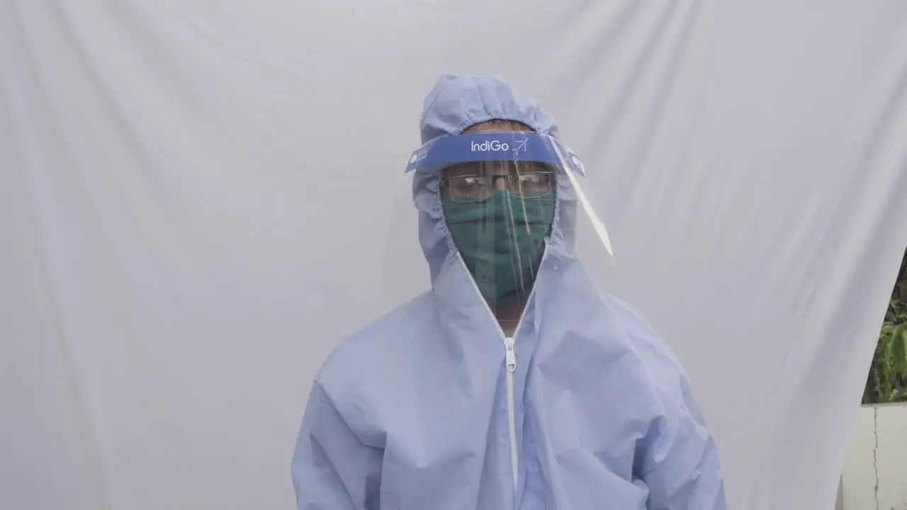 Doctor in PPE kit blue protective suit surgical mask latex gloves