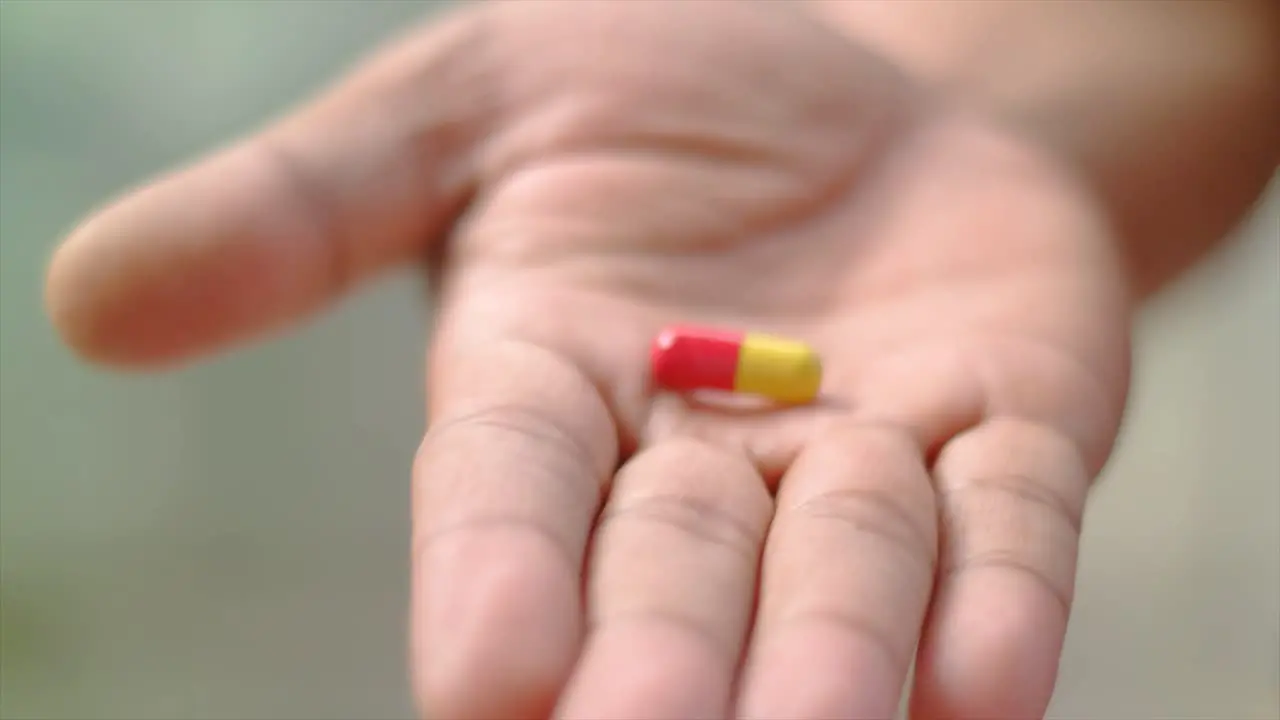 close up of the hand giving one capsule of medicine