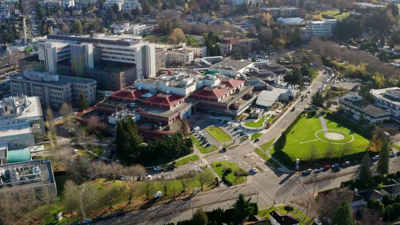 Drone Reveal of Children's Hospital and healthcare research campus with helipad in Vancouver British Columbia Canada UHD aerial tilt up establishing shot on a sunny day