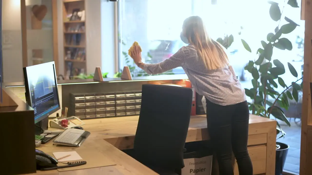 Receptionist office employee disinfects the protective screens in the reception area COVID 19 tourism footage