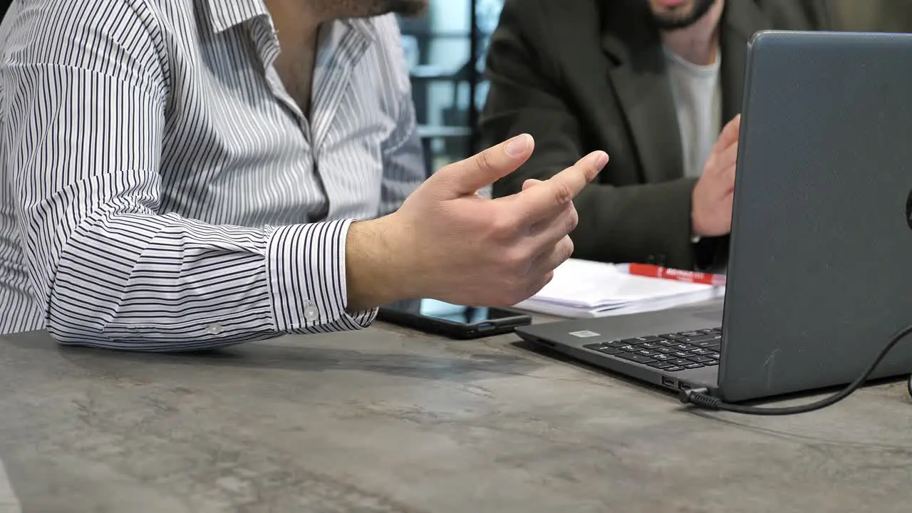 Two unrecognizable office employees discussing problem solution by laptop