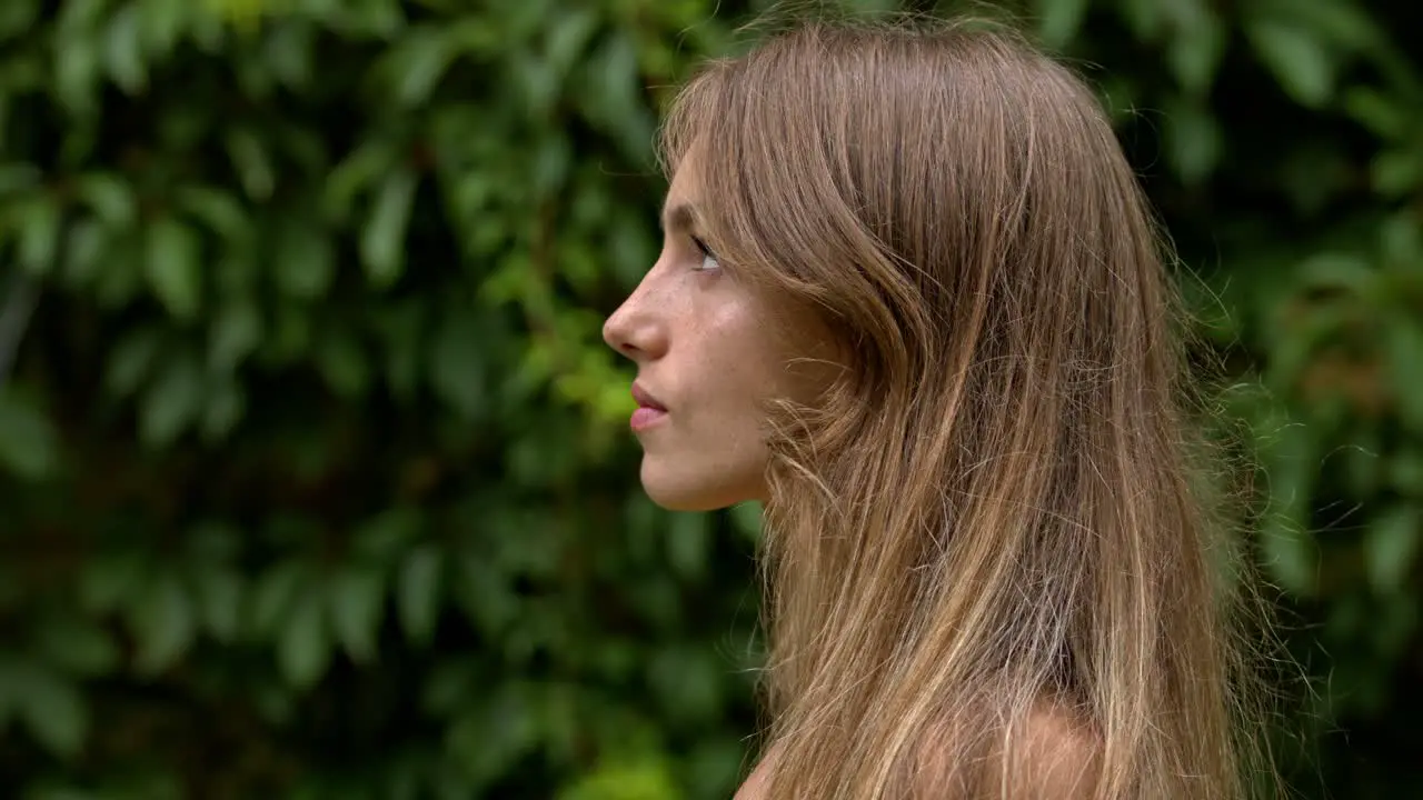 Profile of an attractive young woman with a serious expression on her face against a green floral background