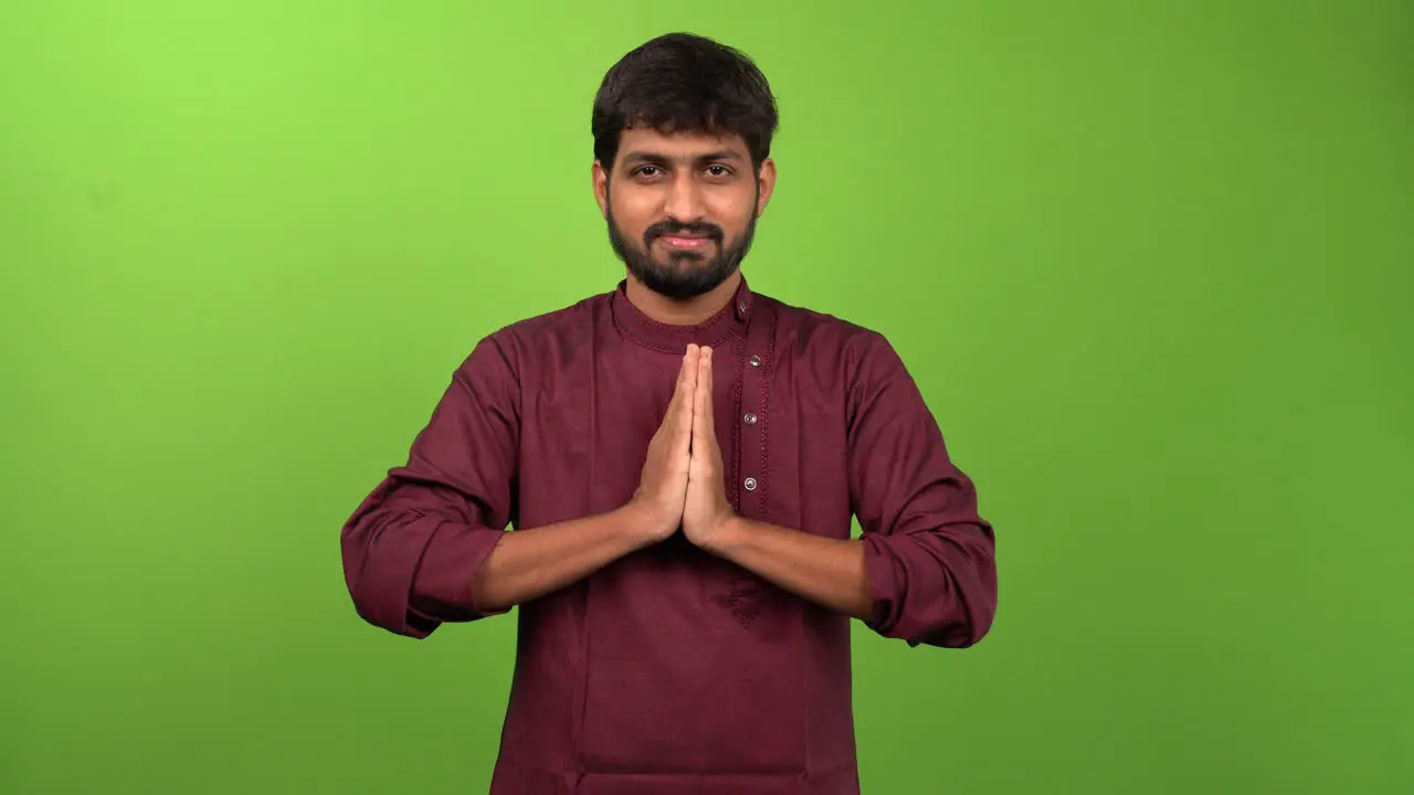 Young attractive man showing namaste gesture isolated on green screen