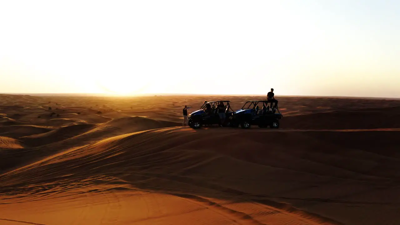 Aerial Shot Of People And Buggy Vehicles On Sand Dunes At Sunset