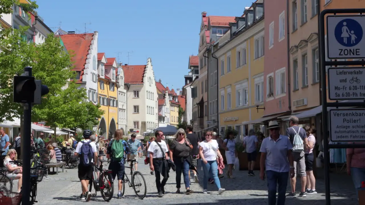 Pedestrians cyclists exploring cobblestone street shops in Lindau Germany