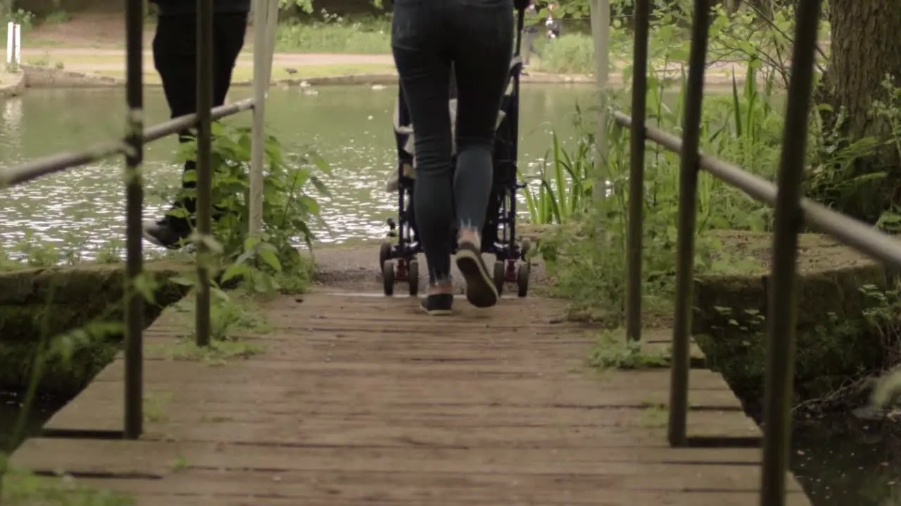 Family wheeling pram across bridge at lakeside