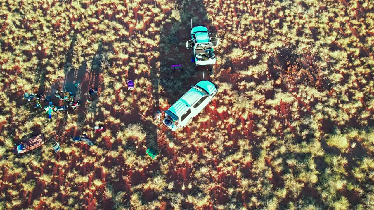 Rising and panning down drone footage of a a group of campers packing up their swags in the Tanami Desert Northern Territory Australia