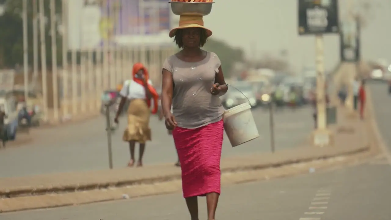 African Female street food vendor walking in slow motion with package on head