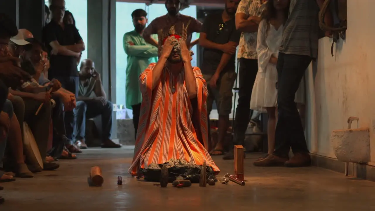 Shaman performing a ritual on knees applying mud to face