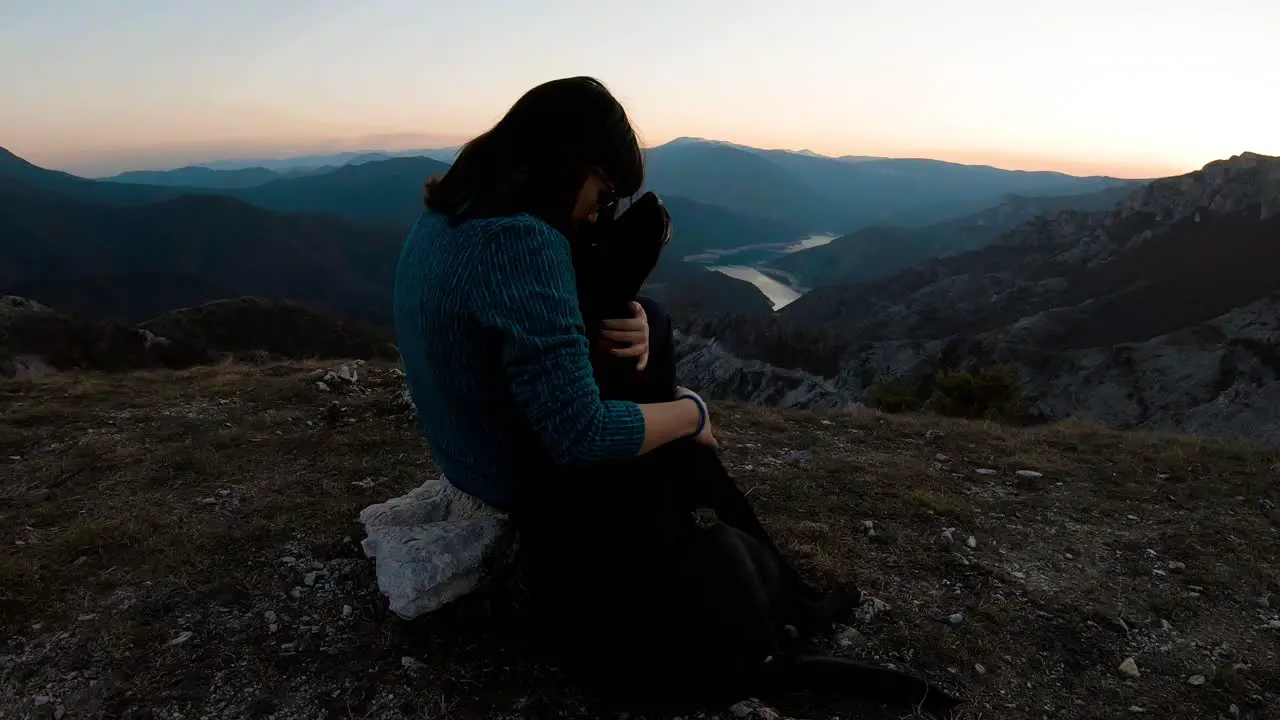 Girl cudling black labrador dog on a mountain