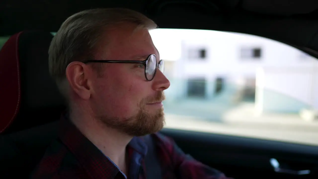 Caucasian Man with Glasses Drives Car and Talks Close Up from Side