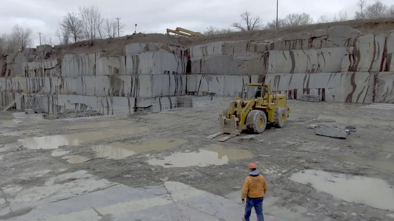 Construction worker walks towards front end loader truck in stone quarry