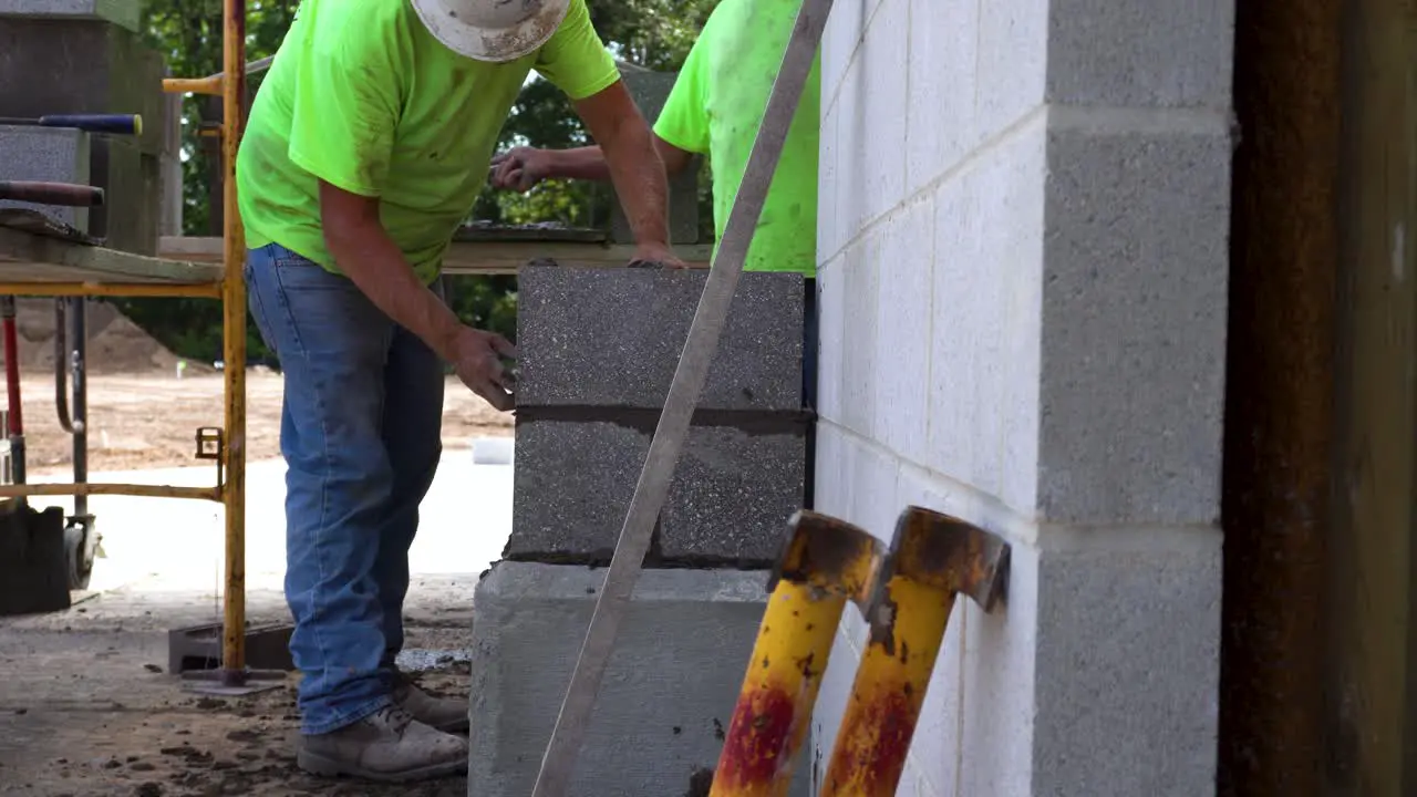 A man brushes grout off of a pillar