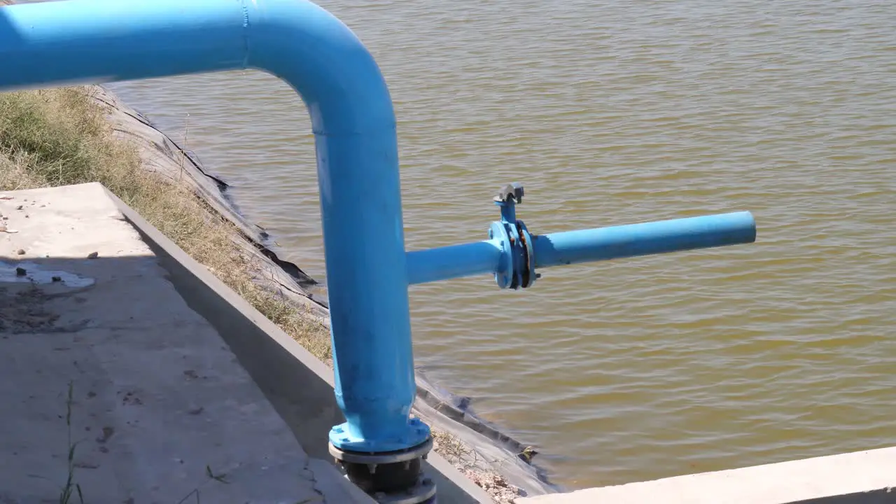 Blue Water Pipe With Outflow Pipe Beside Body Of Water