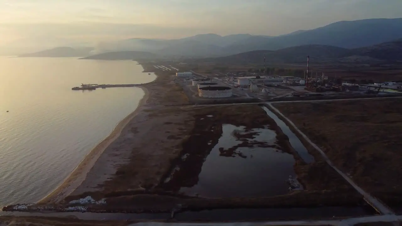 Aerial pan of oil refinery factory next to the Aegean sea at sunset