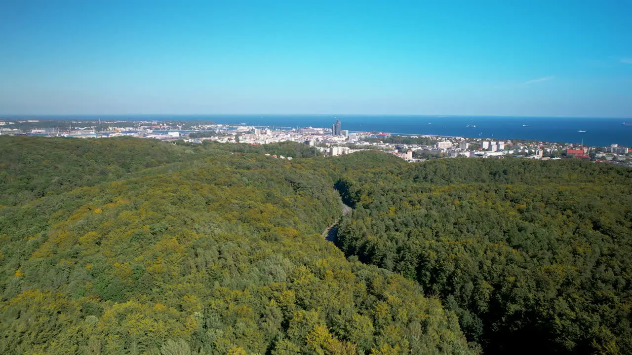 Aerial rising above green trees beautiful panorama of the city of Gdynia from the western side the Gulf of Gdańsk visible from the Witomino district green lungs of the city forest in the city