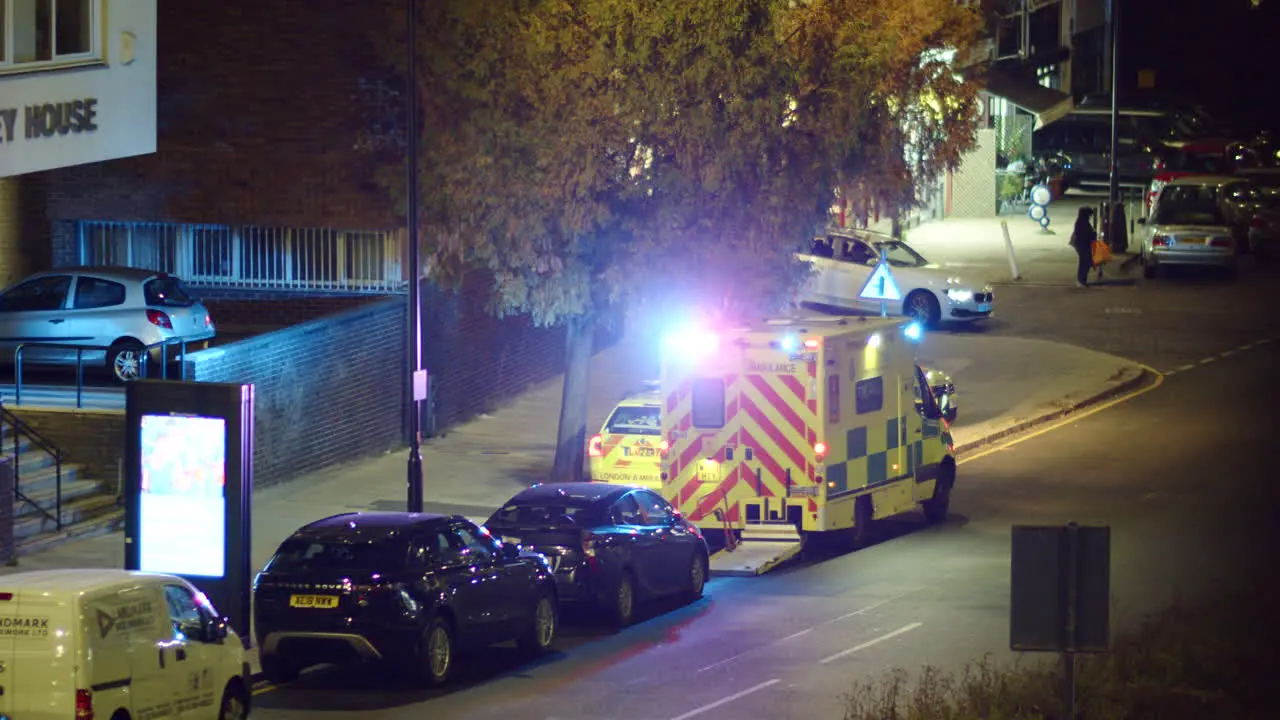 London ambulance with flashing lights parked on a street at night