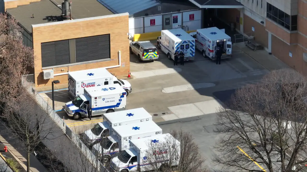 Aerial orbit shot showing parking area of american hospital with parking ambulance vehicle and police car in summer USA