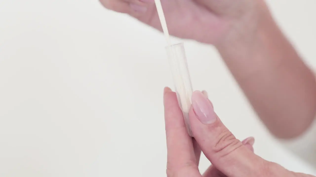 A Person Placing The Cotton Swab Into The Medical Plastic Applicator Tube Covid-19 Swabbing Method Closeup Slow Motion