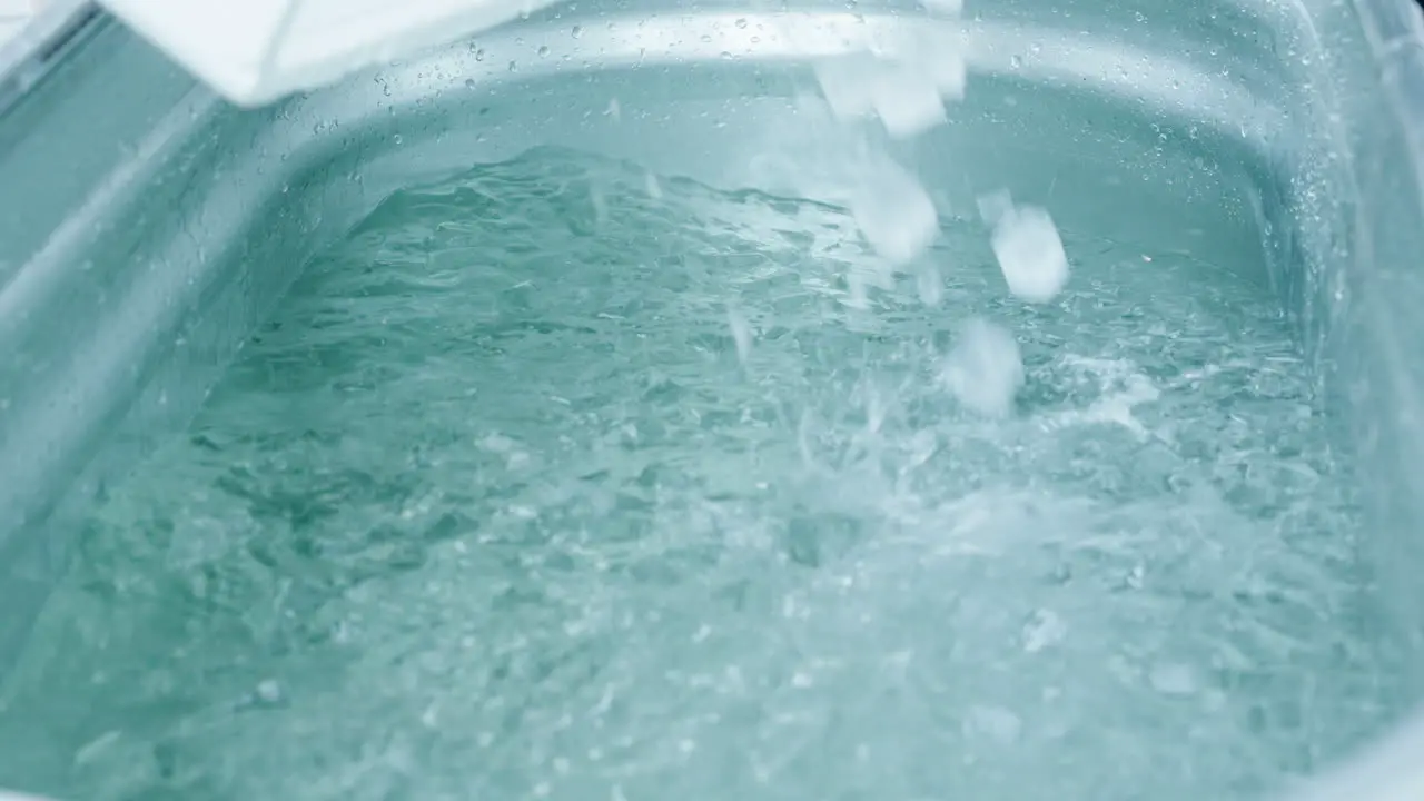 Filling The Steel Bathtub With Ice Cubes For The Wim Hof Ice Bath Experience