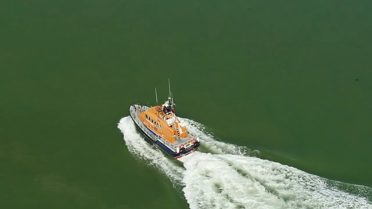 Dramatic aerial tracking shot of a RNLI Lifeboat crew sailing along open water