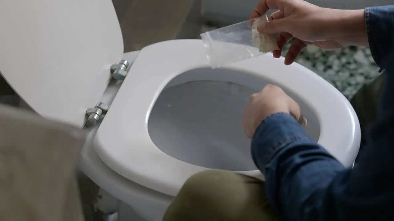 Cropped View Of Man Pouring Out Cocaine In Toilet Bowl In Modern Restroom close up shot