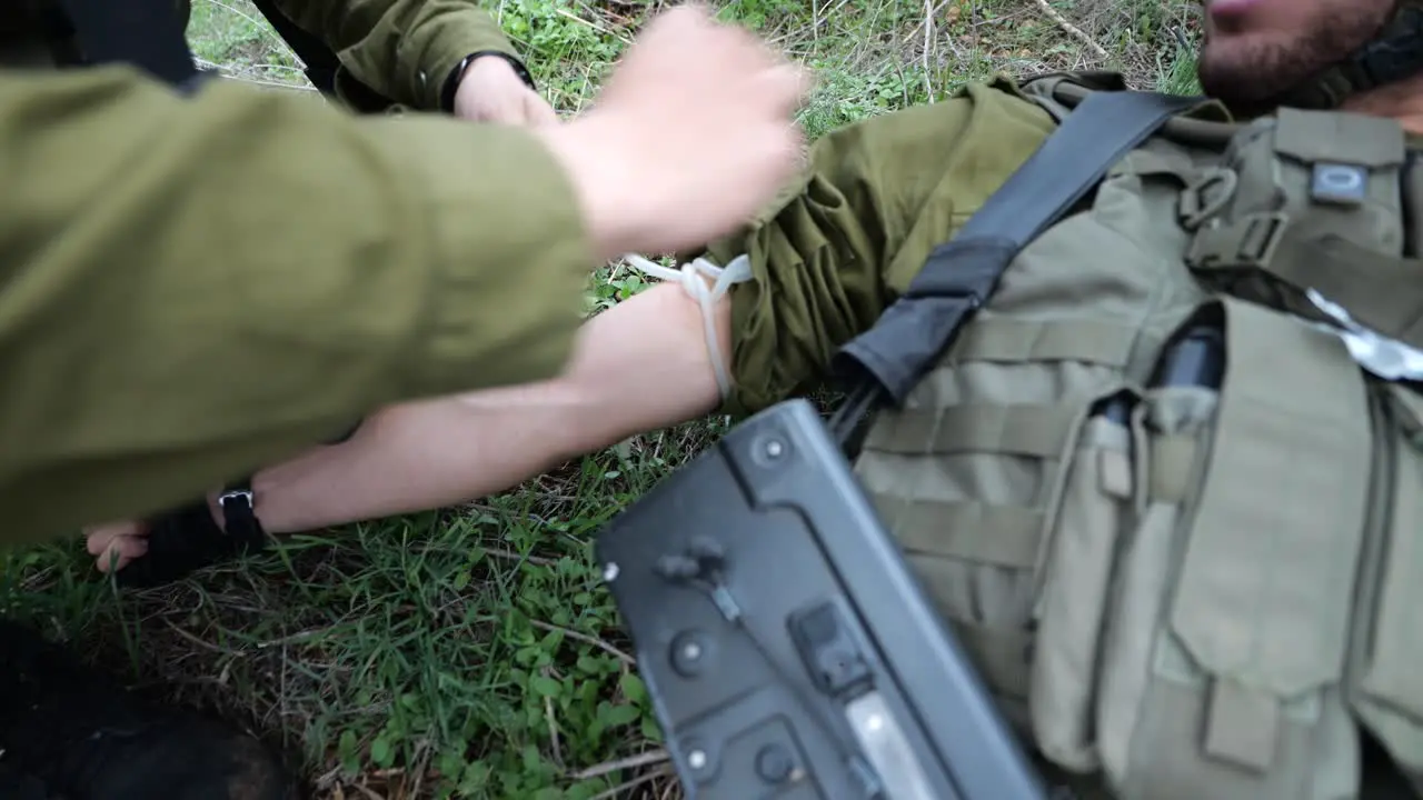 IDF Israeli Soldier Emergency Medical Assistance Or First Aid At Battle Field Applies a Tourniquet on Arm And Injects Needle