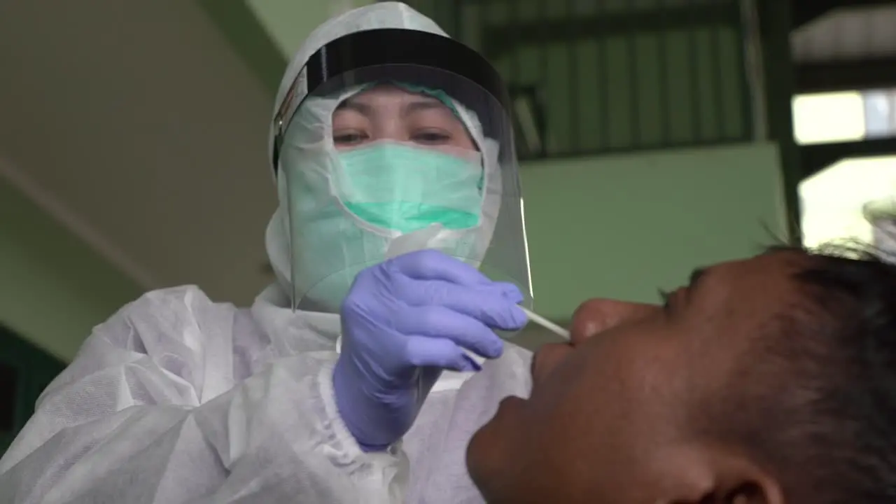 Coronavirus test Medical worker taking swab for coronavirus sample from potentially infected man in isolation gown or protective suit and surgical face mask