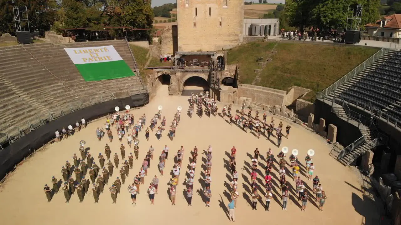 Aerial drone shot orbiting around the arena in Avenches Switzerland with musicians marching out in formation