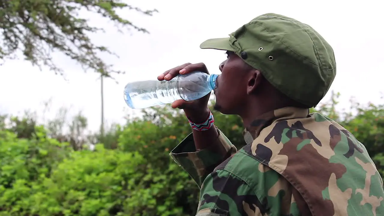 African militant guerilla checks his water amount before sipping on hot day