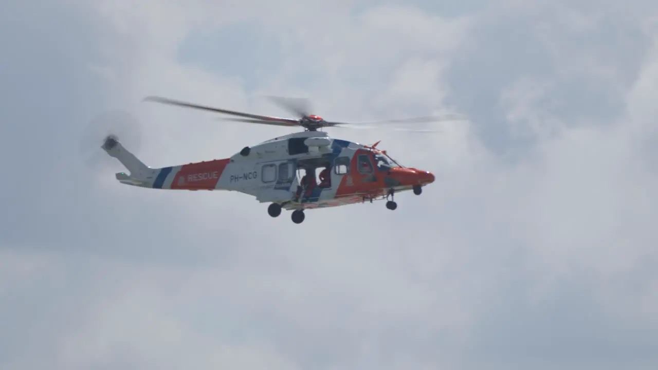 Slowmotion Tracking shot of the Dutch Rescue coast guard helicopter flying in the air