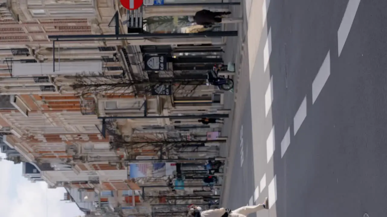 Vertical video of masked people ride bicycles in the city centre of Leuven Belgium