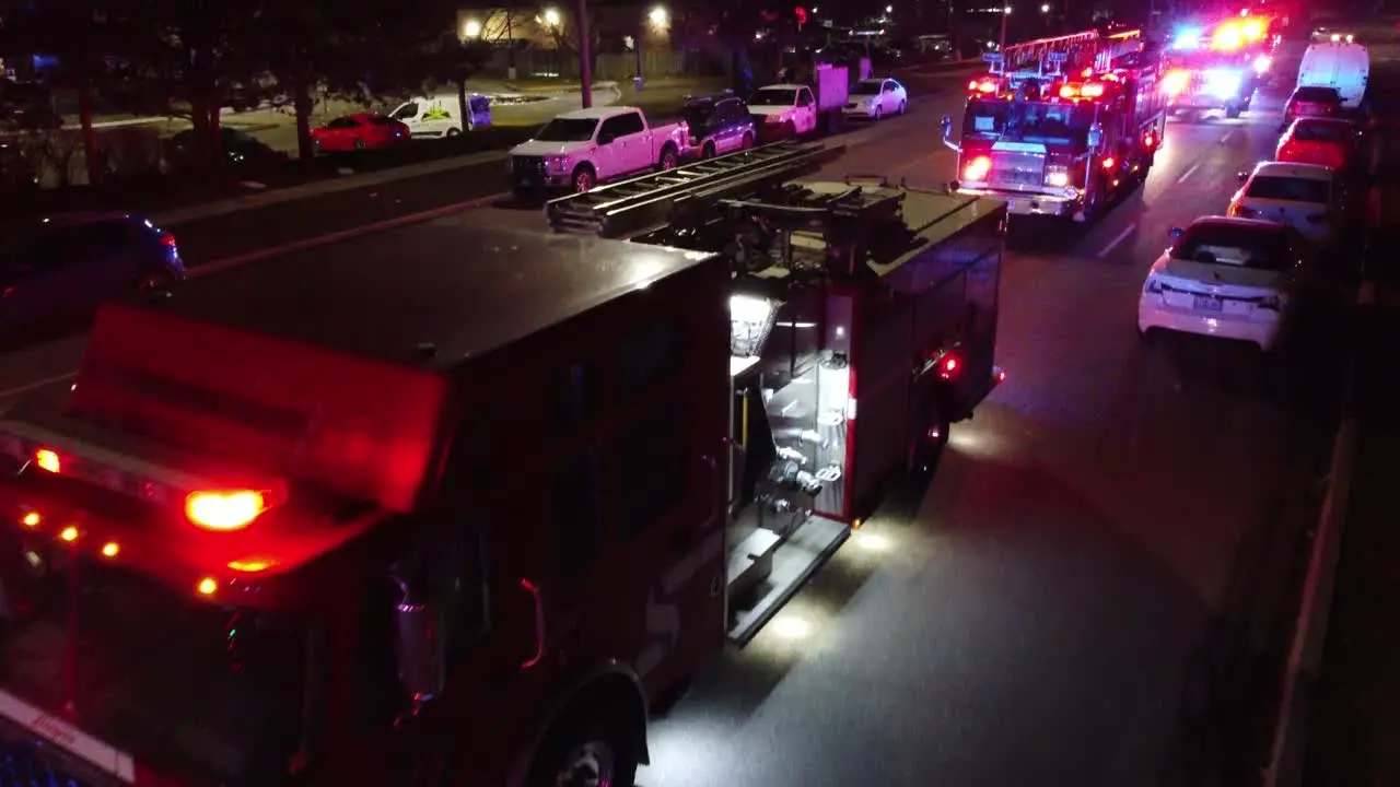 Closeup aerial of firetruck EMS flashing red blue lights at night trucking pan