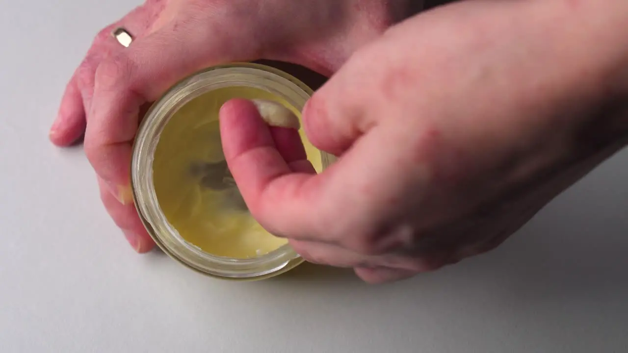 Top down view of woman take homemade hand cream moisturizer from glass jar