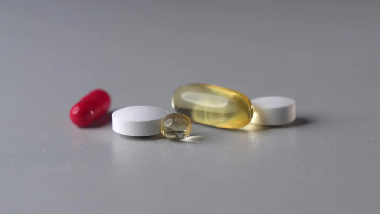 Static zoom in shot of different color medicine pills and capsules on table