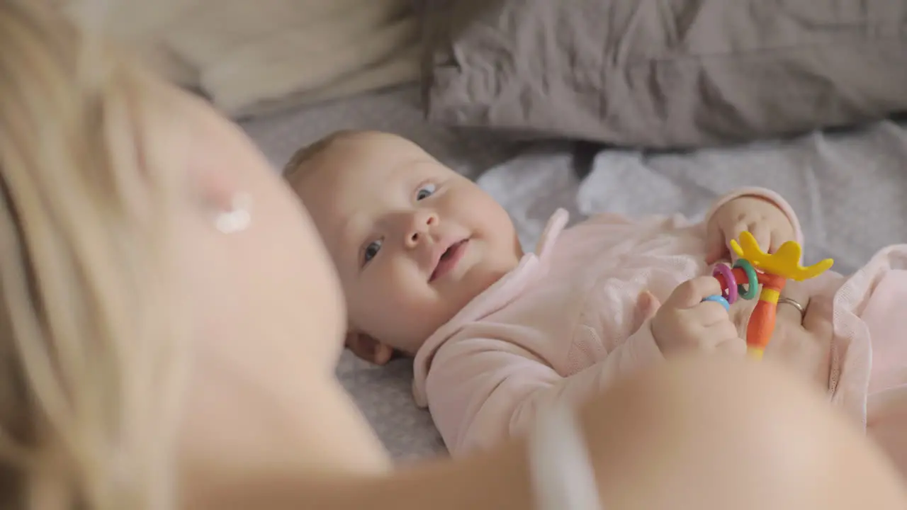 A cute baby girl lying on a back and smiling to her mother