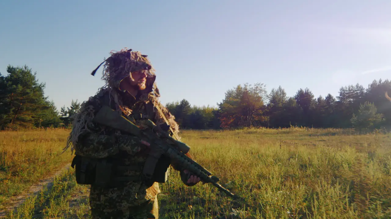 Armed Man In A Camouflage Suit And Weapons Goes On A Country Road