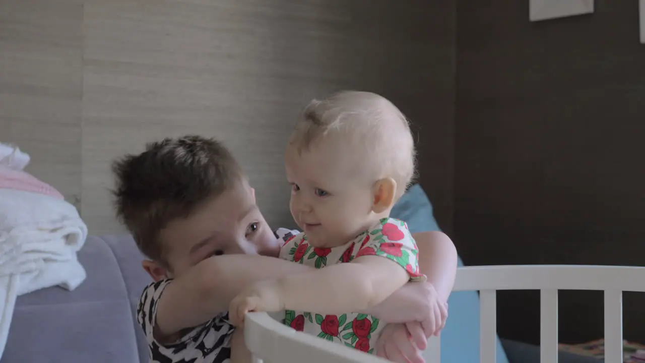 A boy hugging his baby sister in a crib