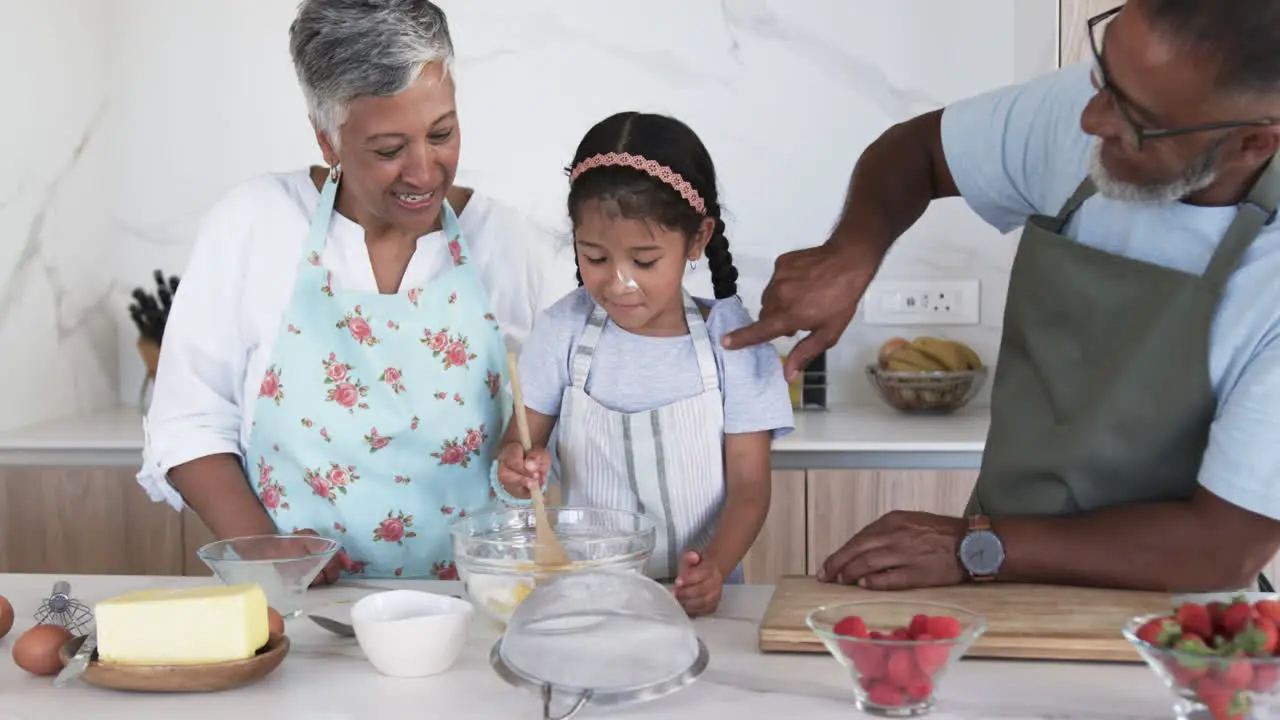 A biracial girl is baking with her grandparents in a modern kitchen